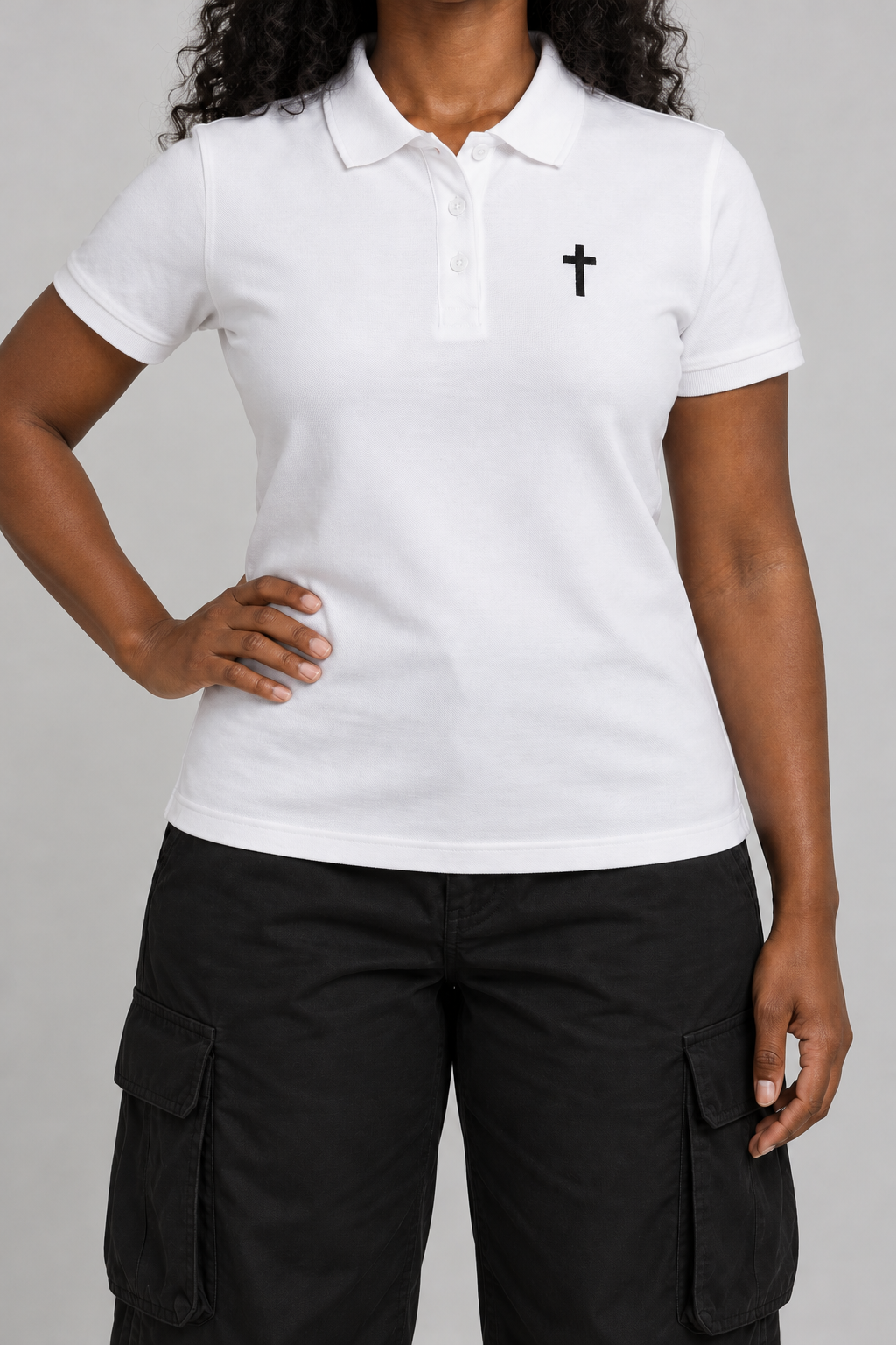 white pique polo with a small black embroidered cross on the chest, on model, front view from the collarbone down with one hand on the hip