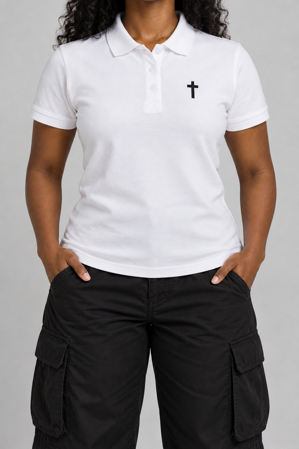 white pique polo with a small black embroidered cross on the chest, on model, front view from the collarbone down with hands in the trouser pockets