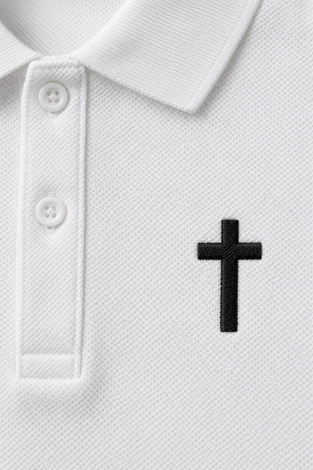 white pique polo with a small black embroidered cross on the chest, close-up of the collar, buttons and embroidered cross