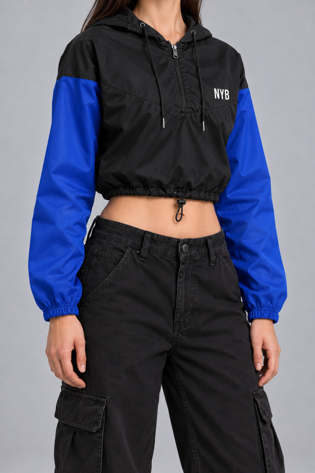 cropped half-zip windbreaker, black with cobalt blue sleeves and a small white NYB on the chest, on model, three-quarter view from the collarbone down