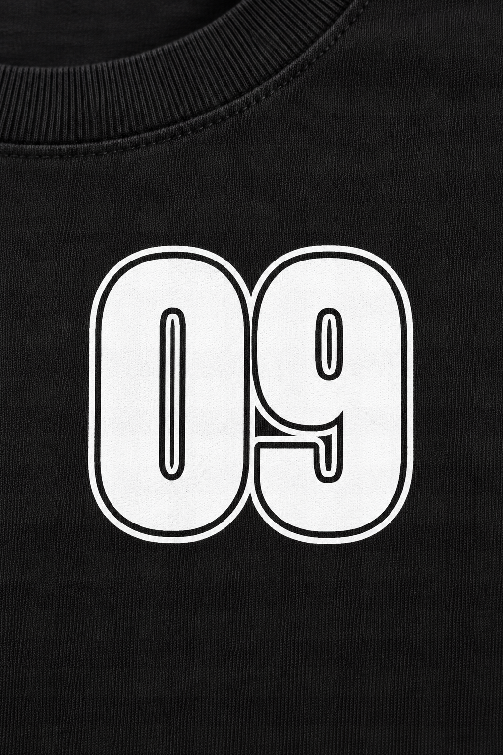 black fitted baby tee with a small white varsity 09 on the left chest, close-up of the white varsity 09 print and ribbed neckline
