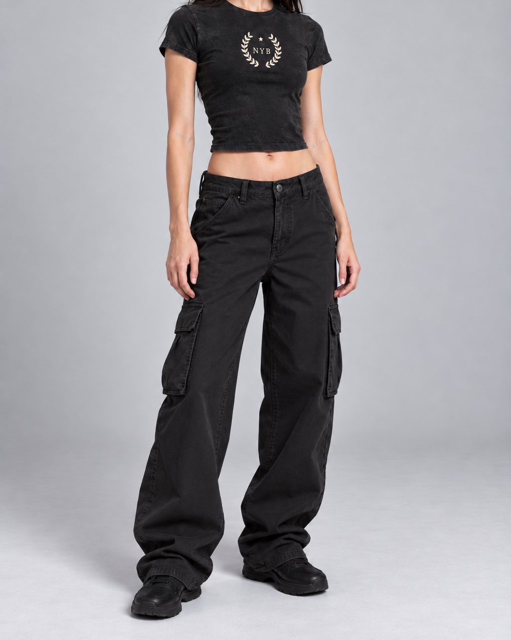 snow-washed black crop tee with a small cream laurel crest reading NYB on the chest, on model, three-quarter view from the collarbone down