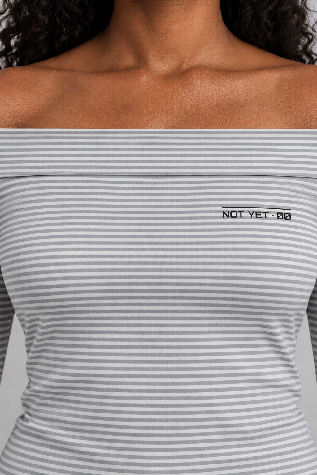 fitted off-shoulder long sleeve top in fine grey and white stripes with a tiny NOT YET 00 line on the chest, close-up of the fine stripes and the tiny NOT YET 00 line