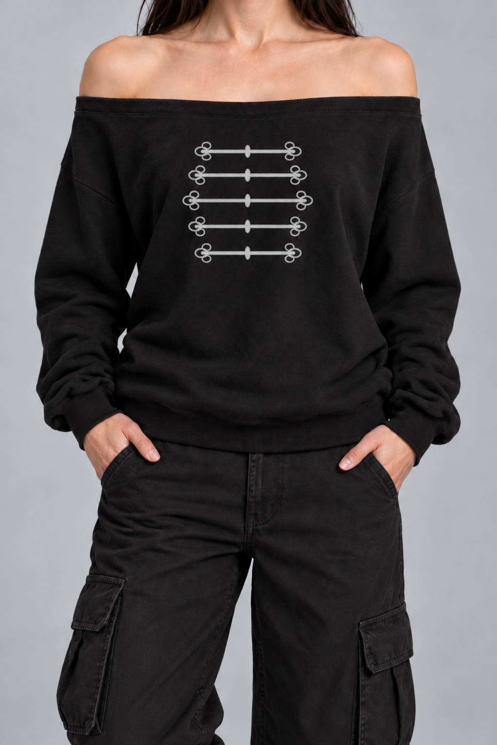 black off-shoulder sweatshirt with silver-grey military frogging across the chest, on model, front view from the collarbone down with hands in the trouser pockets